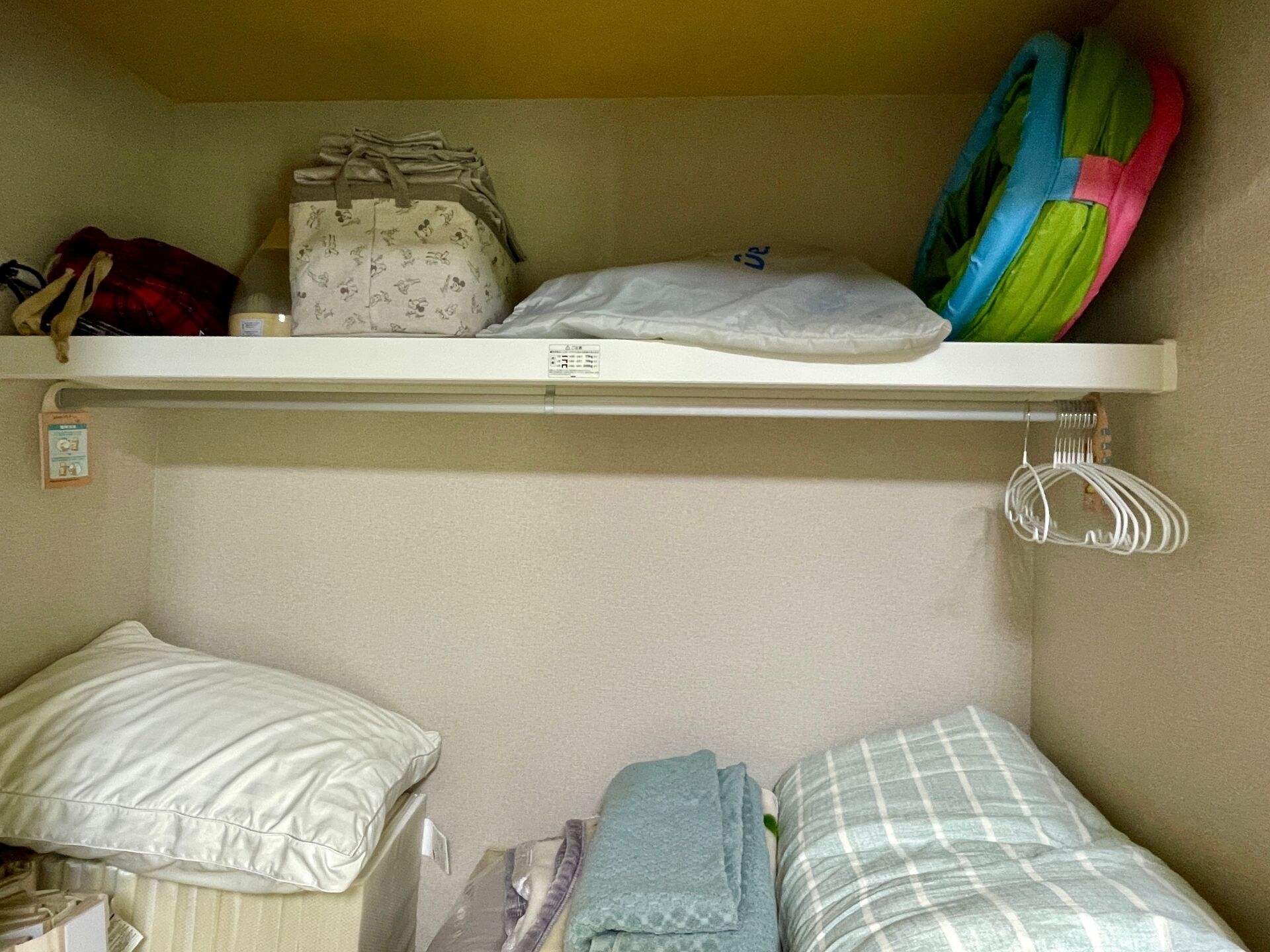 A bunk bed with a shelf above containing a bag, pillow, and a colorful item.