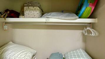 A bunk bed with a shelf above containing a bag, pillow, and a colorful item.
