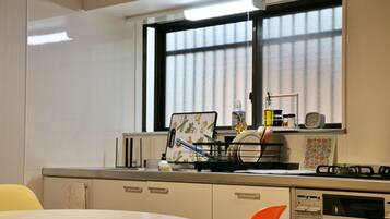 A kitchen with a window, a sink, a stove, and a chair.