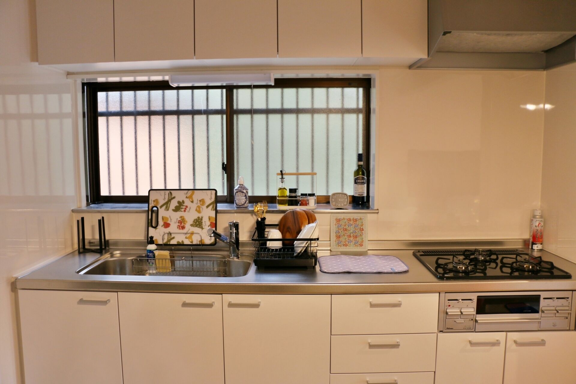 A kitchen with a window, a sink, a stove, and cabinets.
