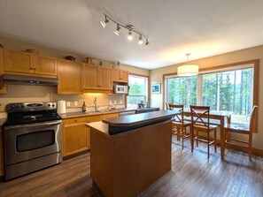 A modern kitchen with wooden cabinets, stainless steel appliances, and a large island with seating.