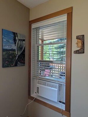 Une pièce avec une fenêtre, un tableau au mur et une petite sculpture.