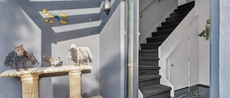 A staircase with a dark carpeted interior leading to a room with a glass door.
