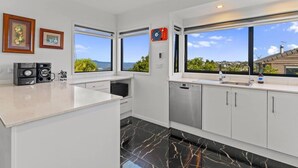 A modern kitchen with a large island, white cabinetry, and a view of the outdoors.