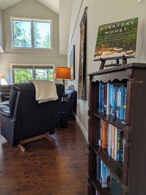 A room with a black leather sofa, a wooden bookshelf, and a framed book on the wall. - Kimberley Mountain Getaway | Ski, Golf & Adventure (Kimberley)