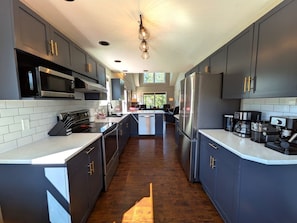 A modern kitchen with dark cabinets, stainless steel appliances, and a central island. - Kimberley Mountain Getaway | Ski, Golf & Adventure (Kimberley)