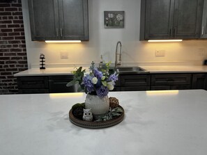 A kitchen with dark cabinets, a white countertop, and a vase with flowers. - Perfect 2-bedroom apartment near all attractions in downtown STL. Arch views! (St. Louis)