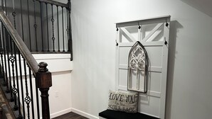 A staircase with a wooden handrail and black balusters, a white bench with a cushion, and a decorative window with a geometric pattern. - Perfect 2-bedroom apartment near all attractions in downtown STL. Arch views! (St. Louis)