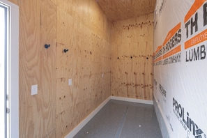 A room with wooden walls and a grey floor, featuring insulation and construction materials.
