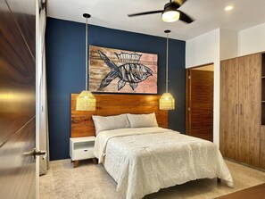 A bedroom with a wooden headboard, a bed with a white bedspread, two hanging pendant lights, and a ceiling fan. - 3-Bedroom Luxury Apartment, Beachfront in Progreso, Yucatán (Progreso)
