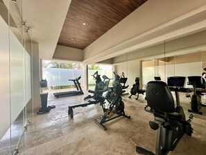 Ein modernes Fitnessstudio mit Trainingsgeräten, großen Fenstern und Blick ins Freie.