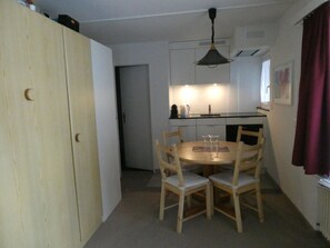 A compact kitchen with a dining area, including a table with chairs and a hanging light fixture. - Paradies 104 Appartement/Fewo, Dusche und Bad, WC, 4-Bettwohnung 4-Bettwohnung by Interhome (Arosa)