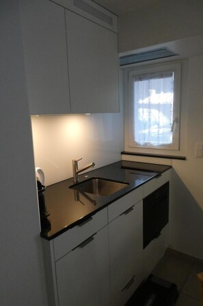 A compact kitchen with a sink, cabinets, and a window. - Paradies 104 Appartement/Fewo, Dusche und Bad, WC, 4-Bettwohnung 4-Bettwohnung by Interhome (Arosa)