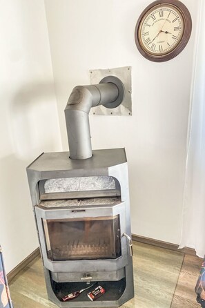 Ein Holzofen mit Schornstein, eine Wanduhr und eine kleine Taschentuchbox auf dem Boden.