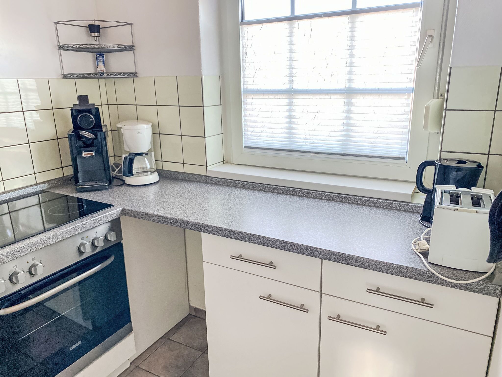 A kitchen with a stove, coffee maker, and kettle.
