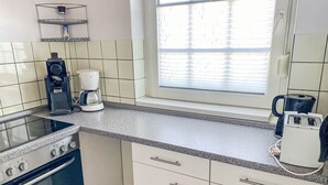 Una cocina con estufa, cafetera y hervidor.