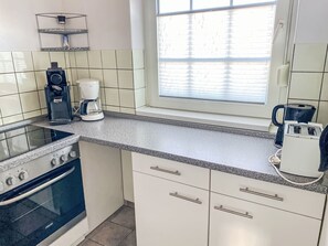 Eine Küche mit Herd, Kaffeemaschine und Wasserkocher.