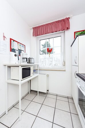 A compact kitchen with a microwave, kettle, and a small refrigerator. - Jupiter by Interhome (Dornumersiel)