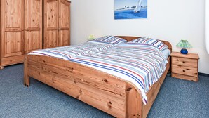 Et soveværelse med en træseng, et natbord, en lampe, et klædeskab og et maleri på væggen.
