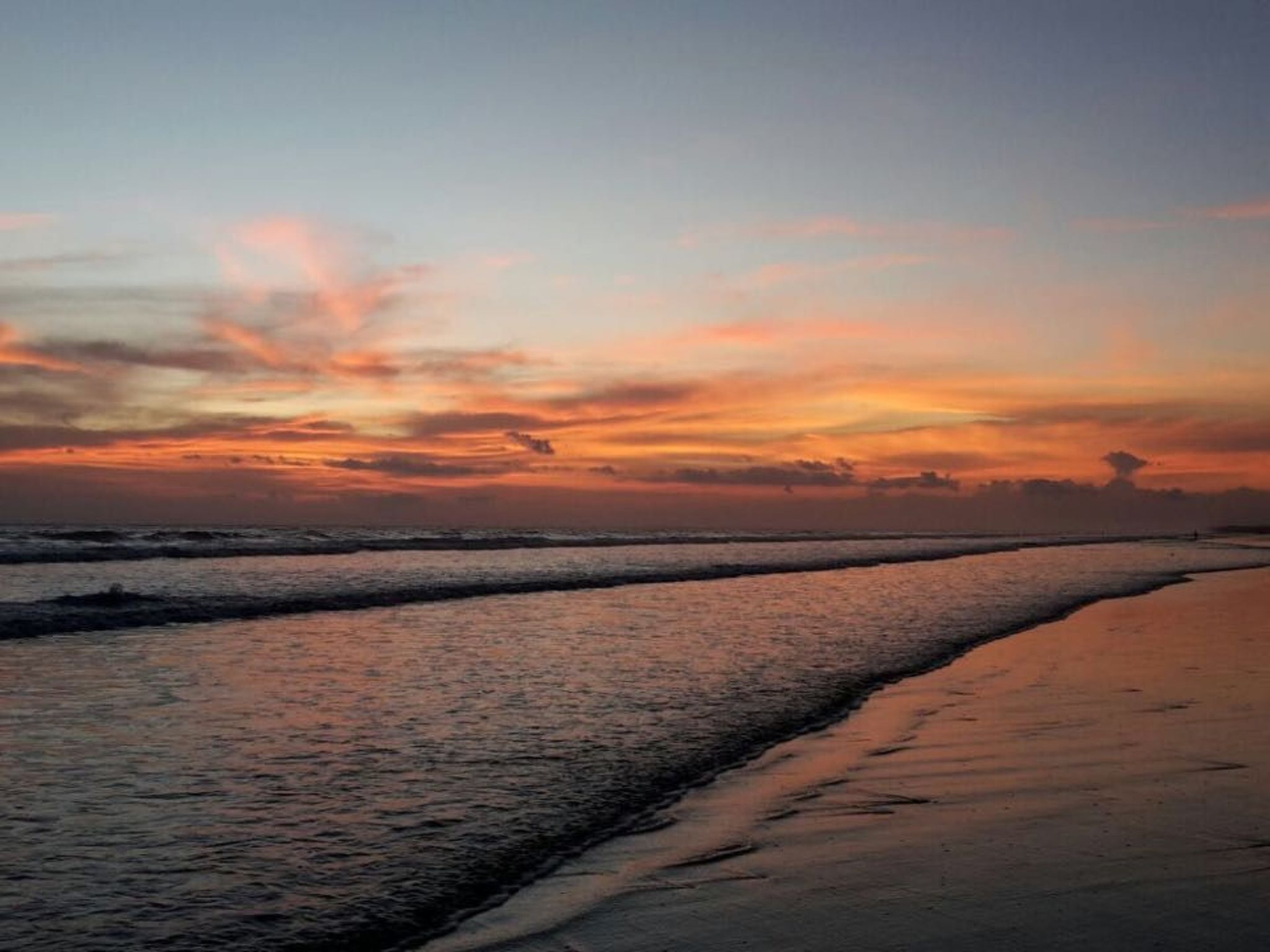 Una playa con olas y un atardecer.