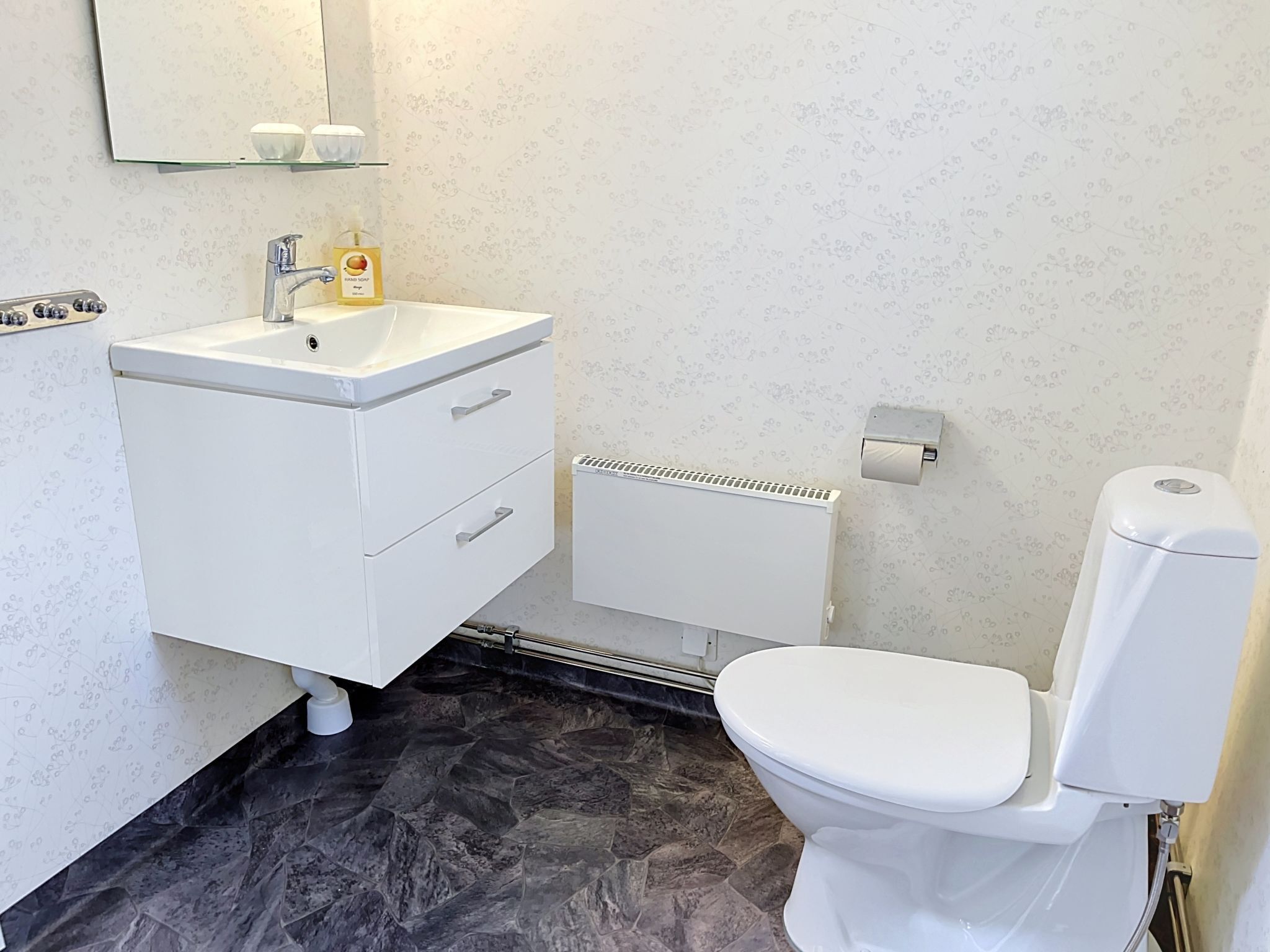 Un baño con lavamanos blanco, inodoro y zona de ducha.
