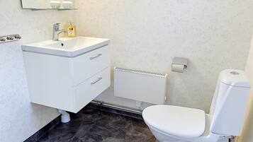 Un baño con lavamanos blanco, inodoro y zona de ducha.