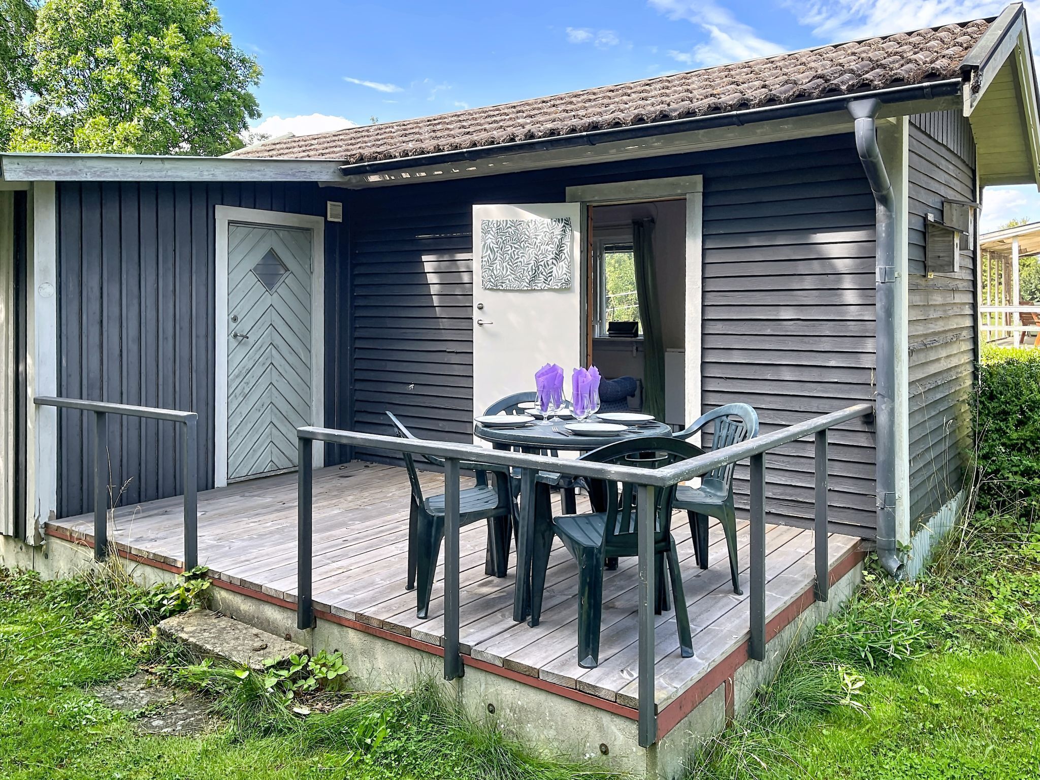 A small wooden cabin with a deck, a door, and a window.