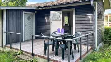 A small wooden cabin with a deck, a door, and a window.