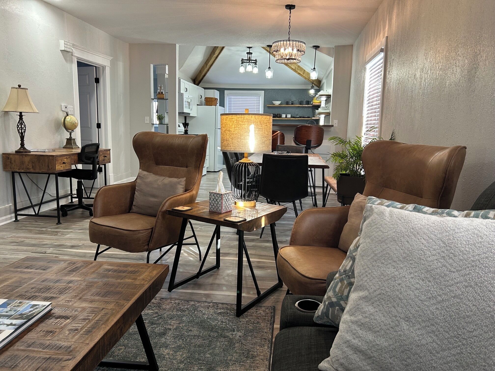 Uma sala de estar moderna com poltronas de couro, uma mesa de centro de madeira e um candelabro.