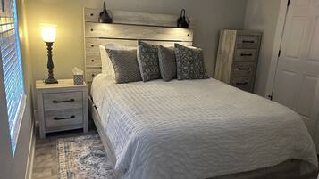 Un dormitorio con cama, mesitas de noche, lámpara, armario y alfombra estampada.