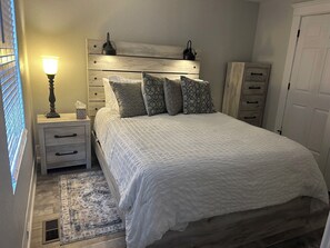 A bedroom with a bed, bedside tables, a lamp, a wardrobe, and a patterned rug.