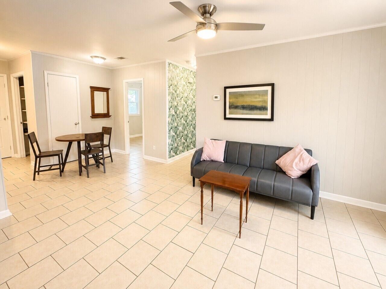 En rummelig stue med en grå sofa, et træ sofabord og et spiseområde med stole og et bord.