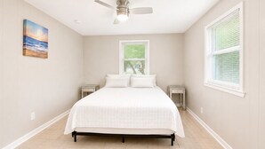 Quarto com cama, ventilador de teto, janela e mesa de cabeceira.