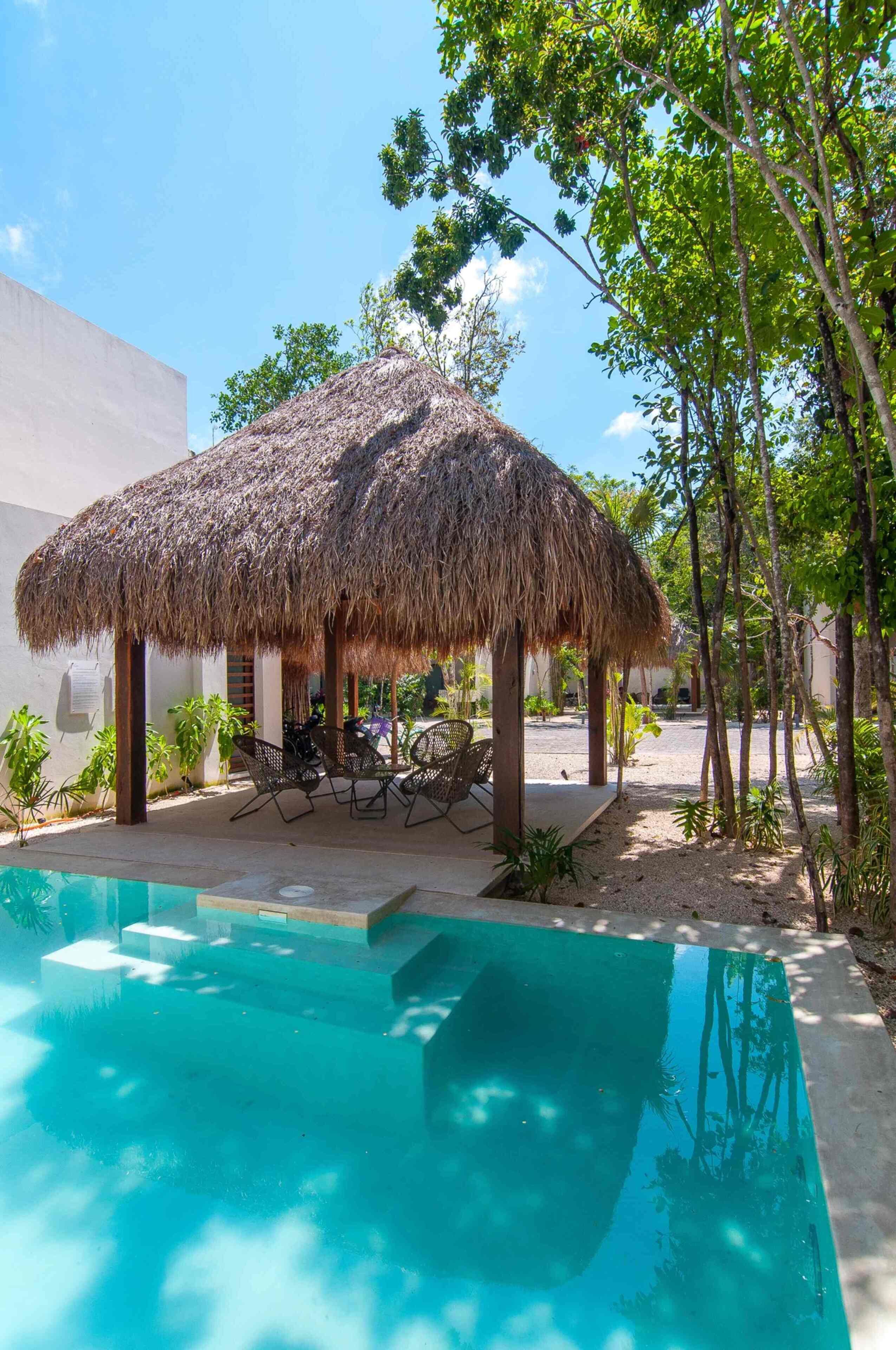 A pool area with a thatched-roof structure and outdoor seating.