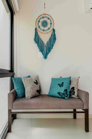 A room with a brown sofa, two teal pillows, and a wall hanging. - 3-bedroom townhome in lovely Tulum with AC and charm (Tulum)