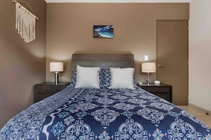 A bedroom with a bed, two bedside tables, a nightstand, a wall-mounted macrame piece, and a framed picture above the bed. - 3-bedroom townhome in lovely Tulum with AC and charm (Tulum)
