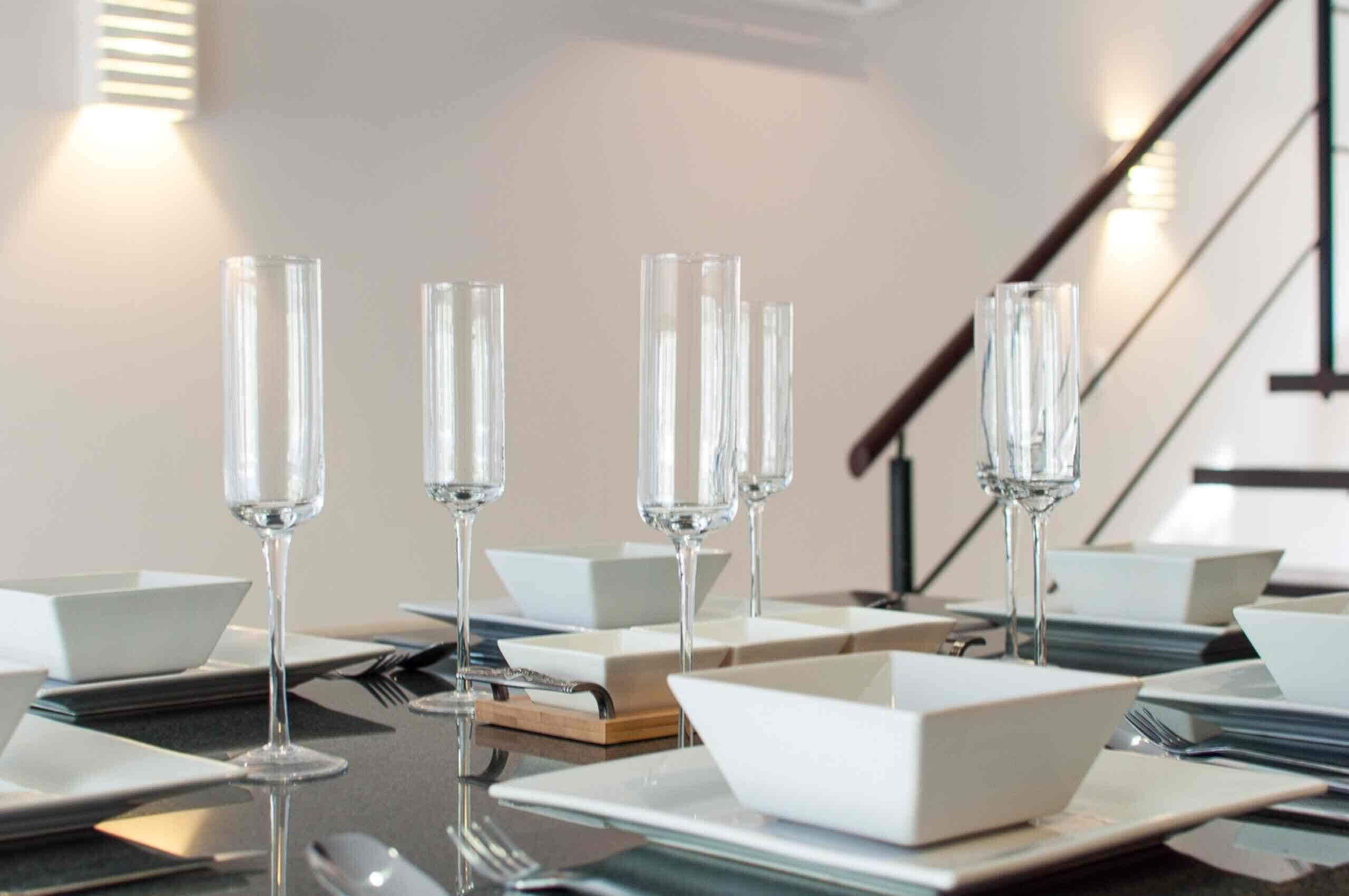 A dining table set with multiple glasses of water, white plates, and cutlery.