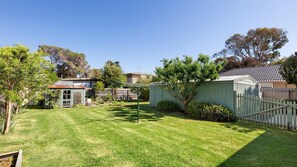 A well-maintained backyard with a lawn, a small shed, and a wooden fence. - Acacia - Point Lonsdale (POINT LONSDALE)