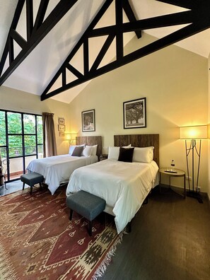 Habitación de hotel con dos camas, un ventanal grande y vistas a zonas verdes.
