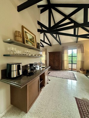 A kitchen with a built-in island, a coffee maker, and a toaster. There is a window with curtains and a view of greenery outside.