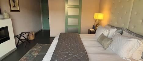 A bedroom with a bed, a bedside lamp, a wall-mounted air conditioner, a framed picture, and a door.
