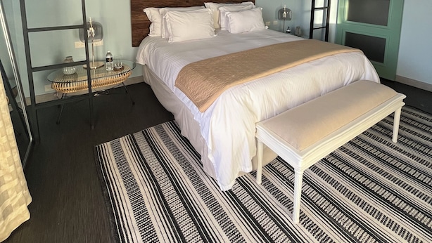 Un dormitorio con una cama litera, una mesita de noche, una lámpara y una alfombra estampada.