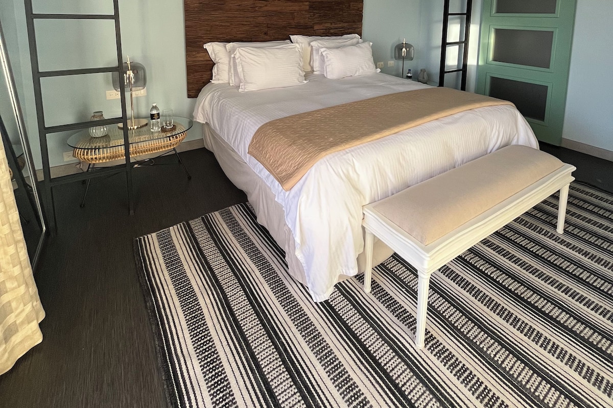 A bedroom with a bunk bed, a bedside table, a lamp, and a patterned rug.