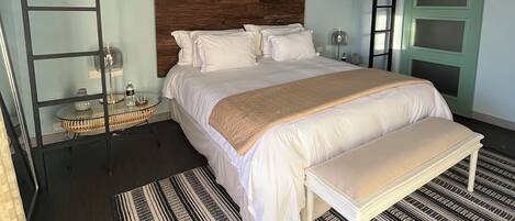 A bedroom with a bunk bed, a bedside table, a lamp, and a patterned rug.