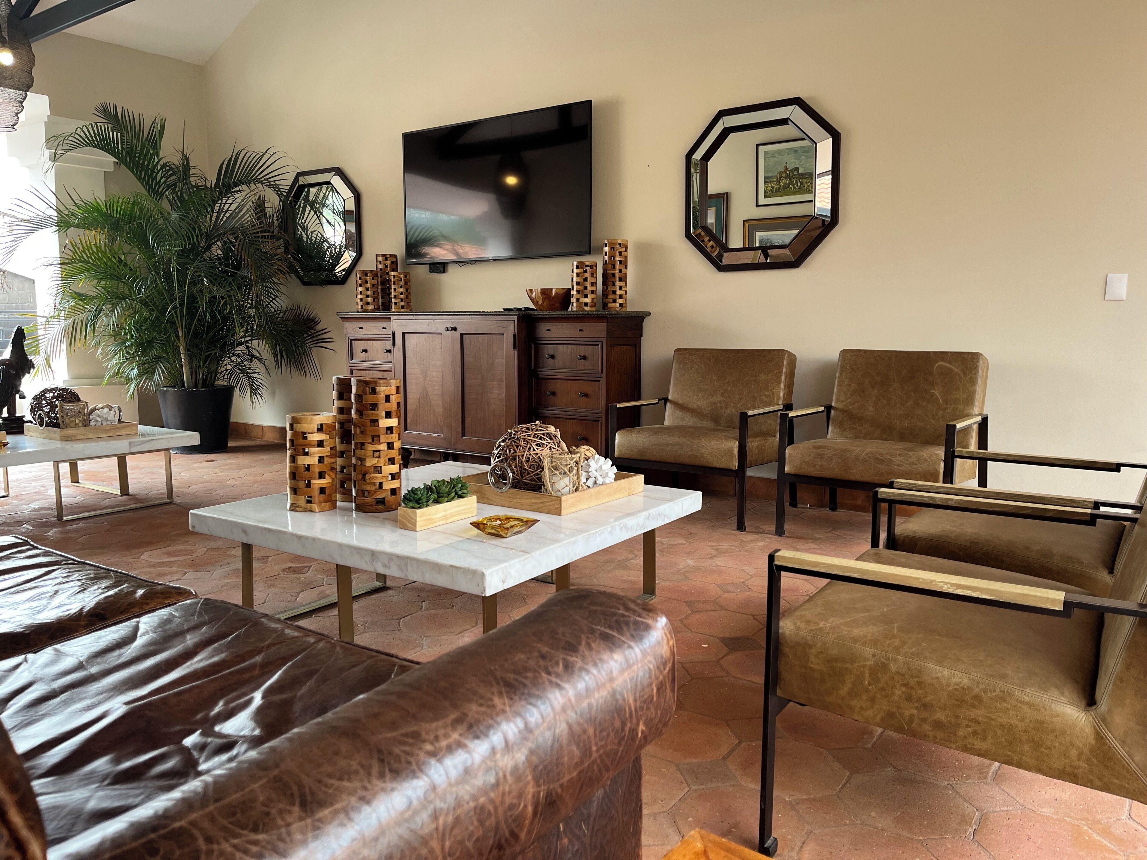 Uma sala de estar com sofá, poltronas, mesa de centro e objetos decorativos.