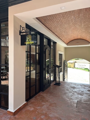A hotel entrance with a sign reading 'CASONA Boutique Hotel,' a tiled roof, and a view of the street. - Boutique Hotel La Casona  (Valle de Angeles)