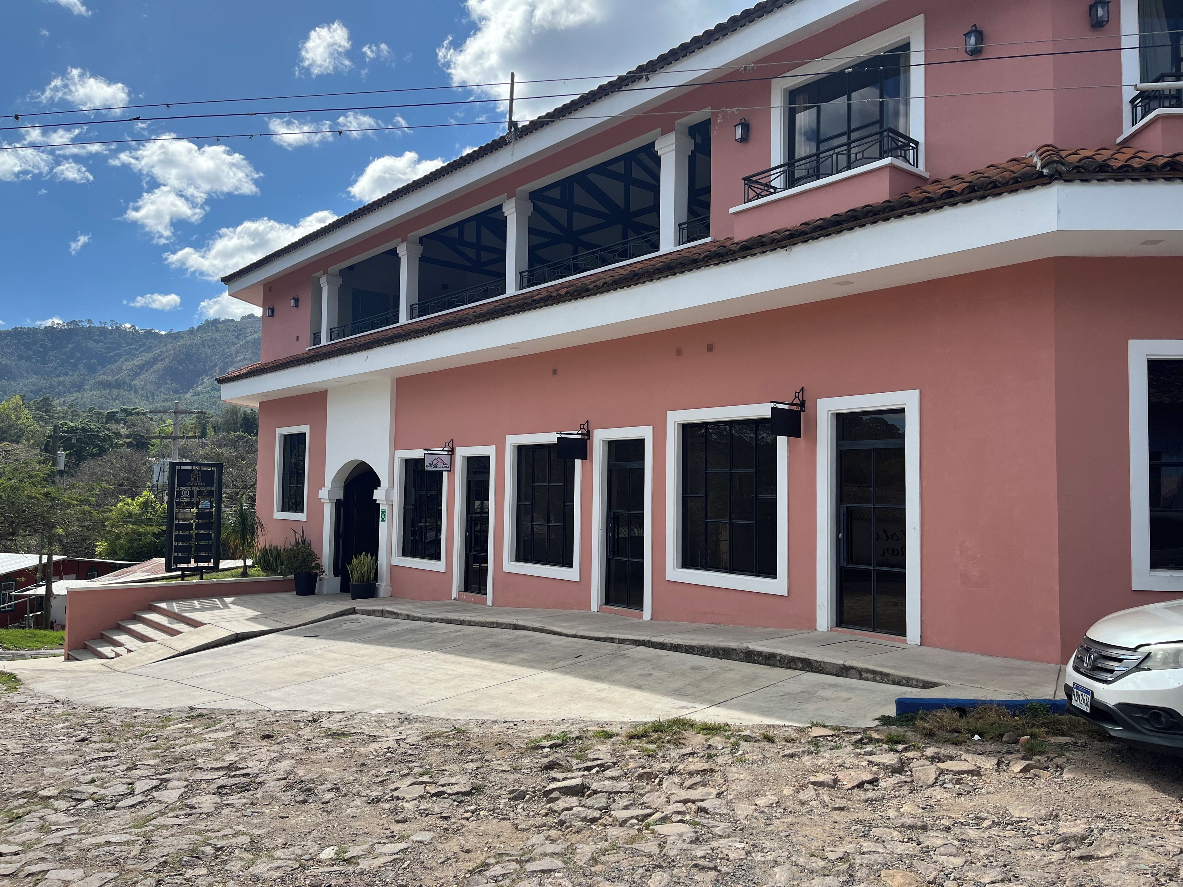 Un edificio de dos pisos con fachada roja, múltiples ventanas y entrada pavimentada.