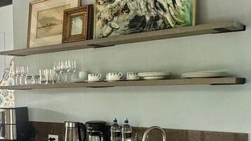 A kitchen with a marble countertop, stainless steel appliances, and a painting above the sink.