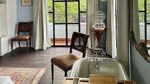 Un baño con bañera, un espejo grande y una ventana con cortinas.