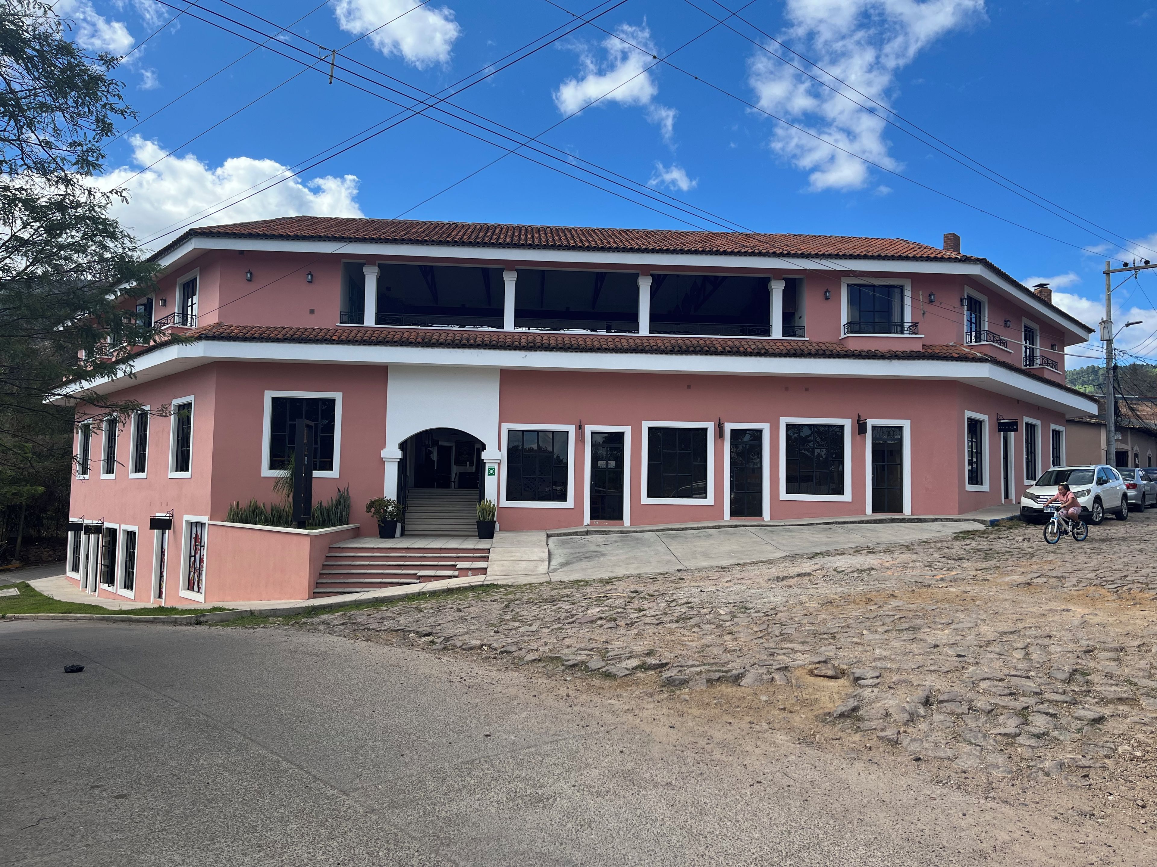 Um edifício de dois andares com telhado de telhas vermelhas, várias janelas e uma escadaria que leva à entrada.